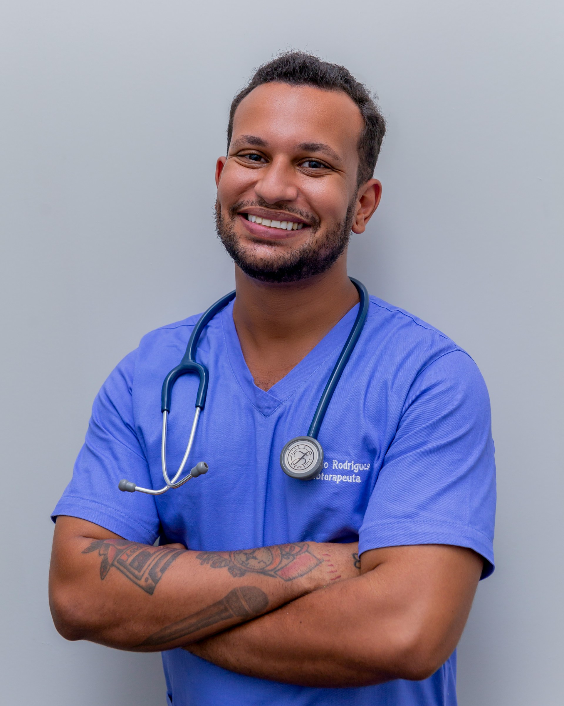 Young doctor wearing blue uniform and stethoscope smiling at the camera