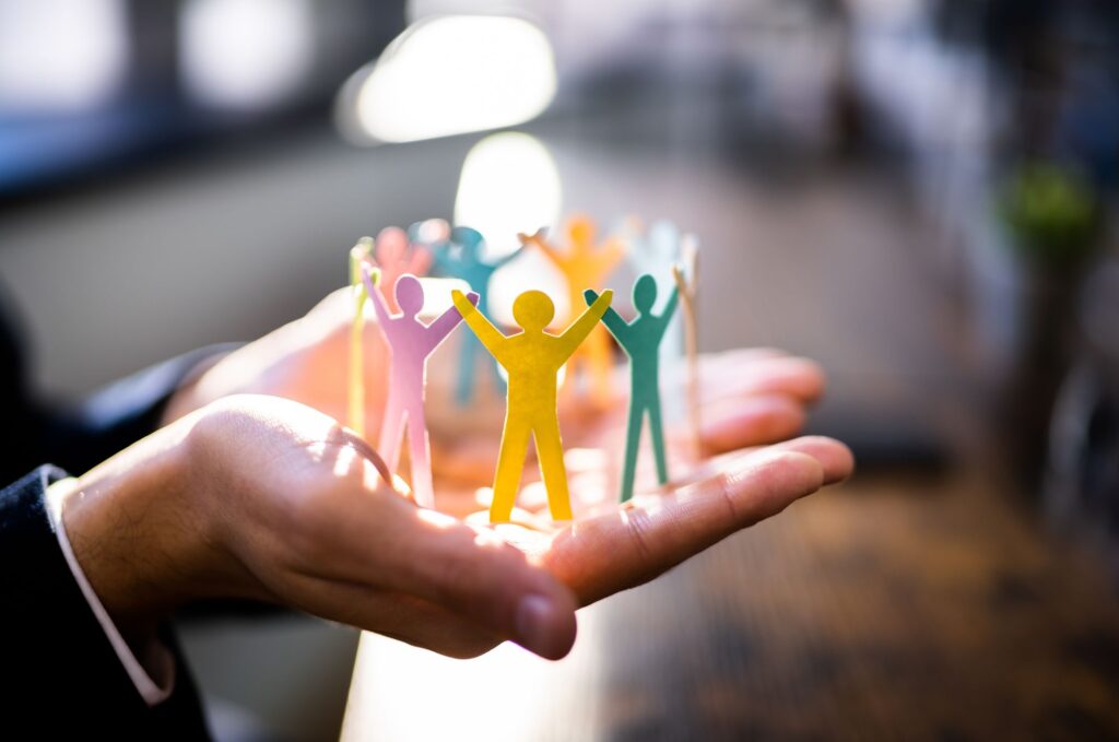 Person holding coloured figurines of people in their hands